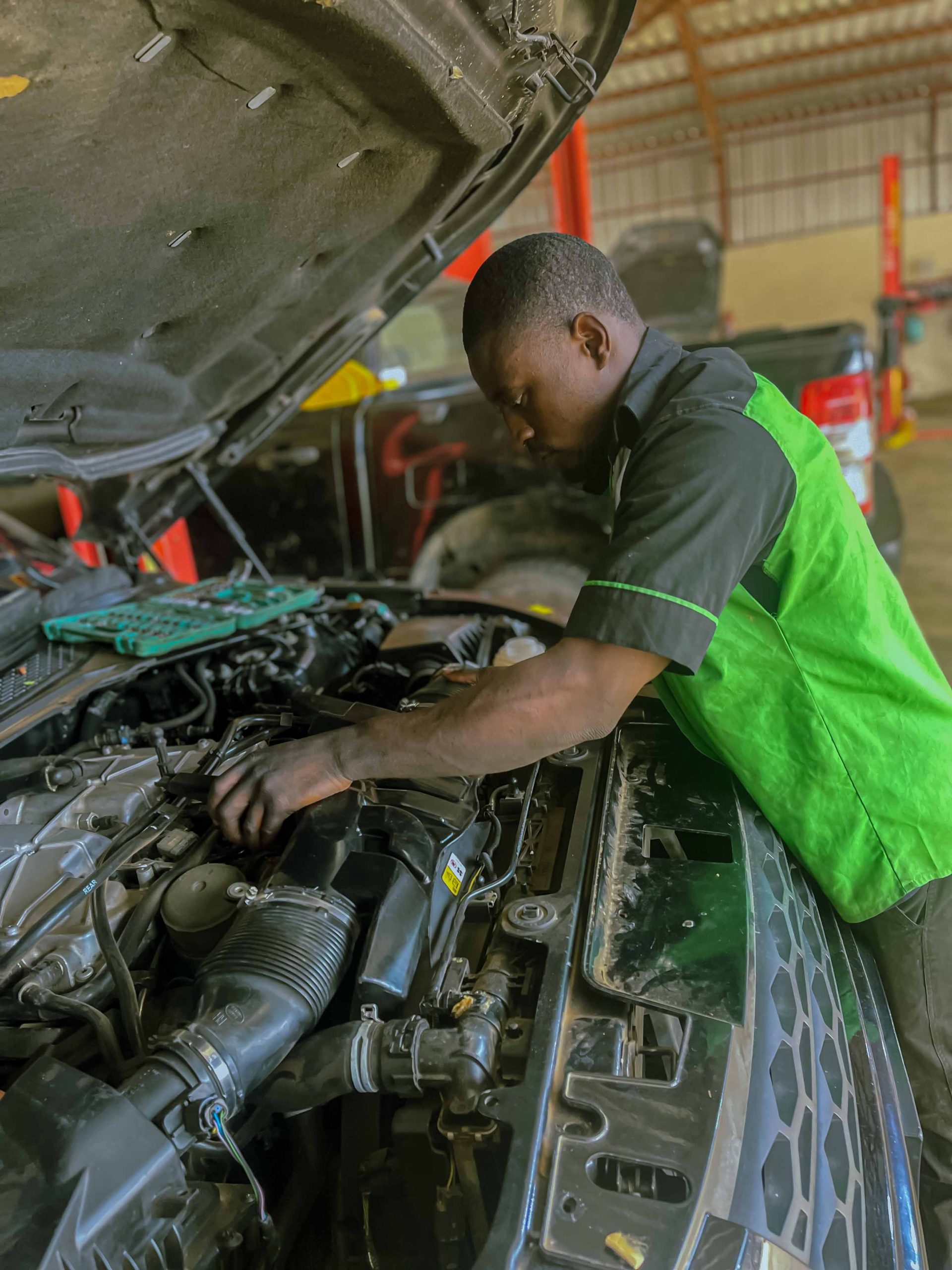 Taharish mechanic leaning into engine bay for repair
